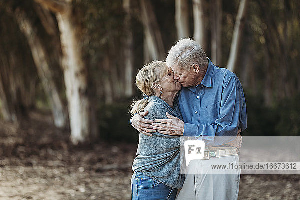 Porträt eines älteren erwachsenen Paares im Ruhestand  das sich im Wald küsst