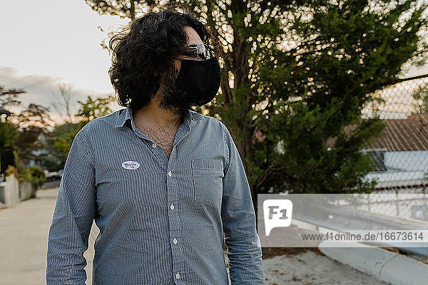 Man with mask and I voted sticker looking off camera