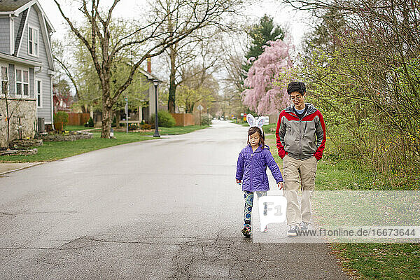 Ein Kind mit Hasenohren geht mit seinem Vater auf der Straße im Frühling spazieren
