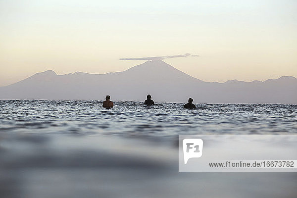 Surfer auf dem Surfbrett auf dem Meer  die auf eine Welle warten  Vulkan Rinjani