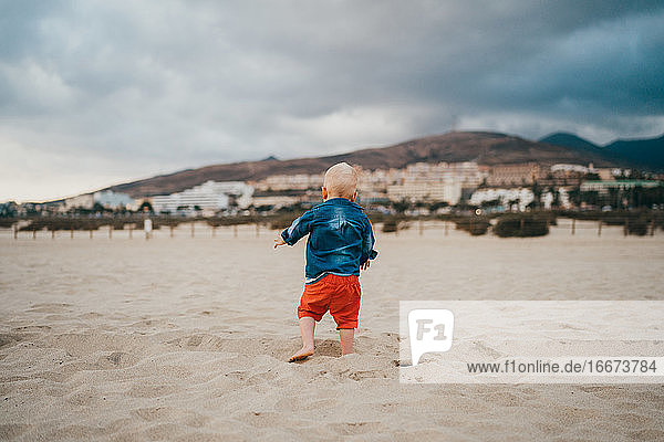 Junge spielt am Strand an einem bewölkten und kalten Tag