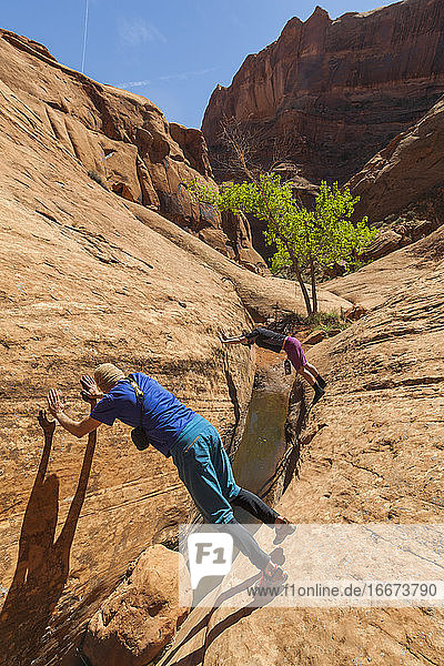 Wanderer überbrücken einen Sandstein-Slot-Canyon in der Nähe des Escalante River  Utah
