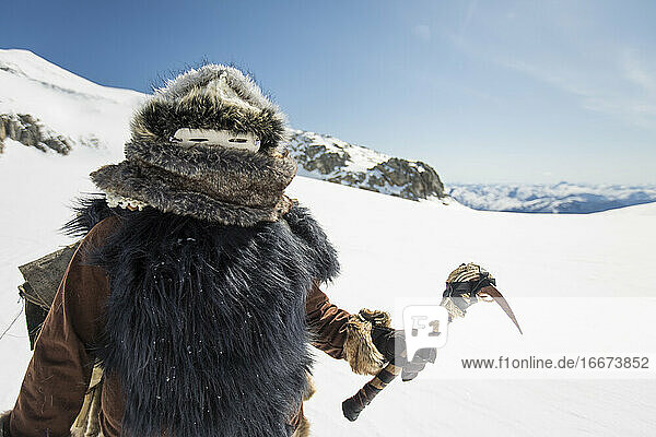 Ein indianischer Jäger hält eine traditionelle Axt in den Bergen.