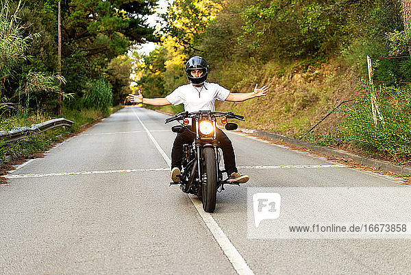 Young man on a vintage motorcycle on a mountain road at sunset