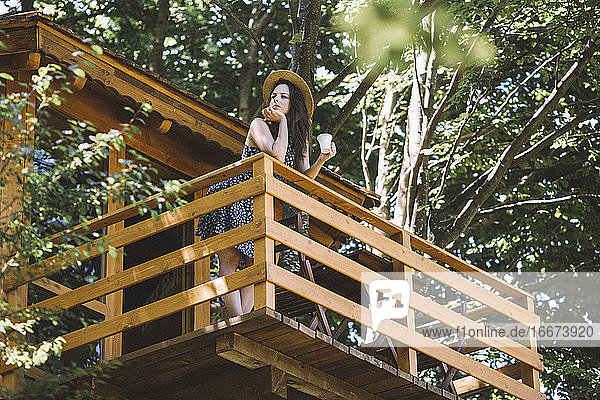 Junge Frau steht auf dem Balkon des Baumhauses