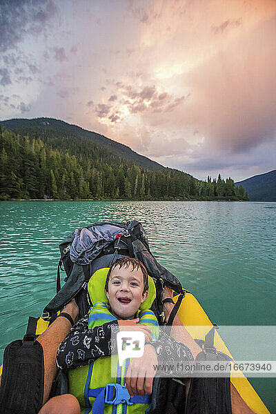 Young boy smiles  laughs during father son paddling trip.