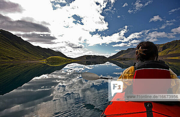 Frau rudert Seekajak auf einem stillen See in Zentralisland