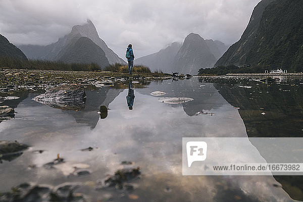 Junge Frau steht vor der Aussicht auf den Mitre Peak im Milford Sound  NZ