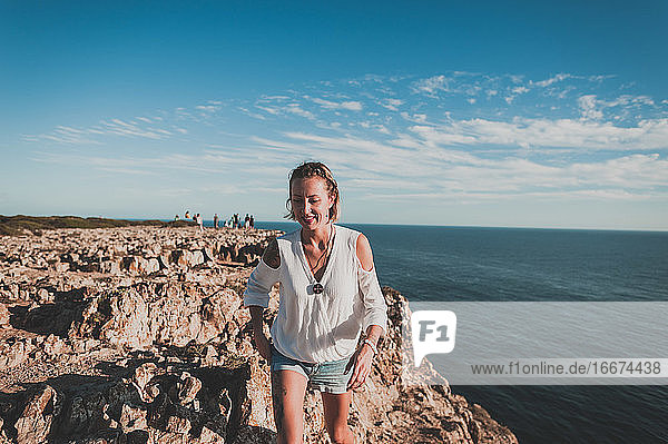 Junge Frau auf einer Klippe mit Blick auf das Meer im Sommer in Portugal