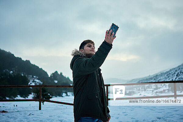 Ein junger Mann macht an einem verschneiten Tag ein Selfie mit seinem Mobiltelefon
