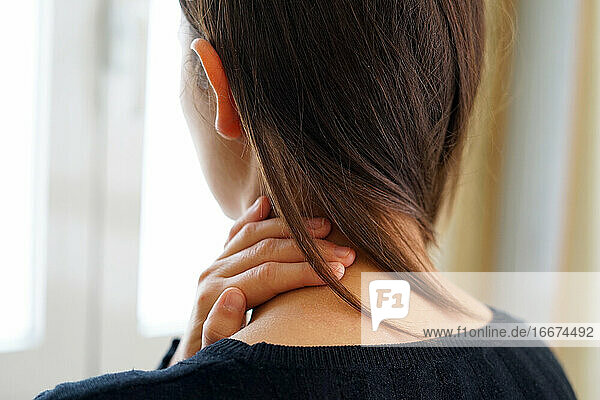 Frau mit Nackenschmerzen  die ihren Nacken berührt. Nackenschmerzen Konzept.