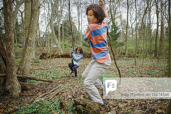 A boy and girl play in a forest together nature on a cool gray day