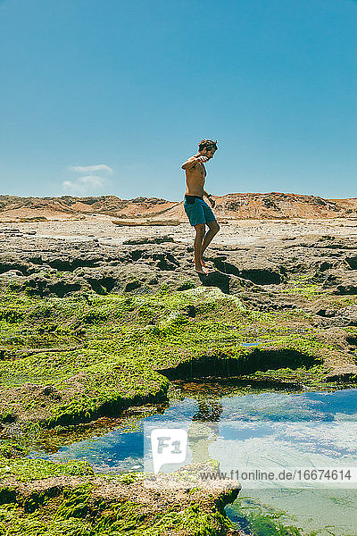 Junger Mann bei der Erkundung von Meeresklippen im Sommer in Baja  Mexiko.