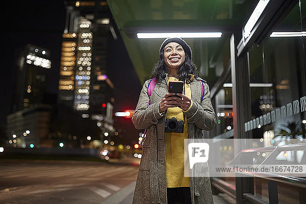 lächelnde Frau  die in den Straßen von Mexiko mit ihrem Handy telefoniert