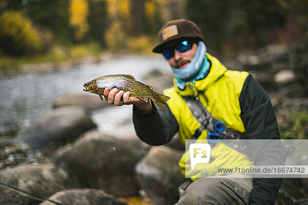 Man holding fish at Roaring Fork River