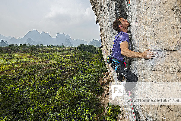 man climbing on the limestone cliff 'White Mountain' in Yangshuo