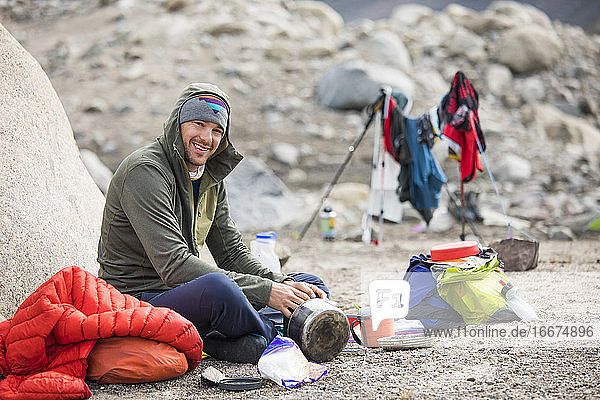 Portrait of climber sitting down for a meal at camp.