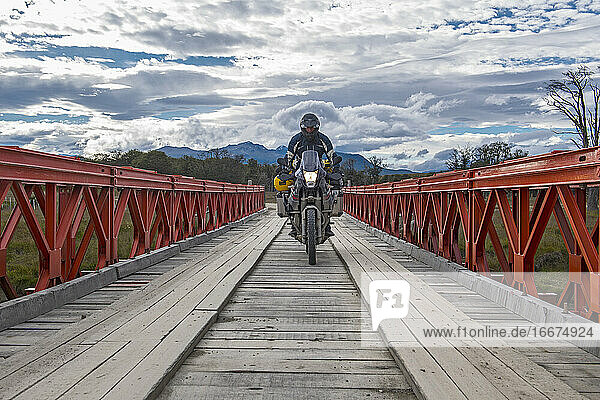 Mann auf Geländemotorrad beim Überqueren einer Holzbrücke