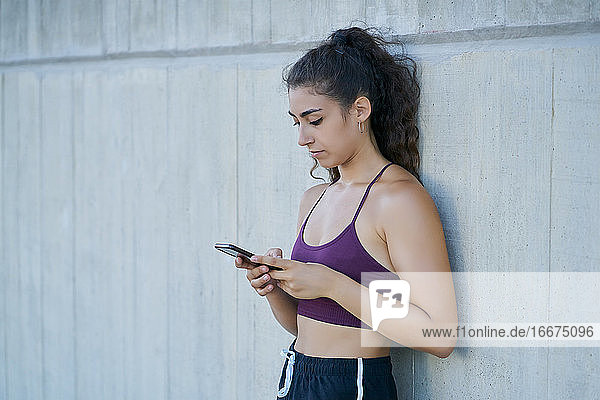 Frau in Sportkleidung schaut auf ein Smartphone