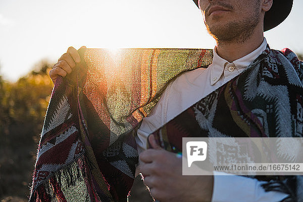 Mann im Freien hält Poncho gegen die Sonne  ländliche Szene