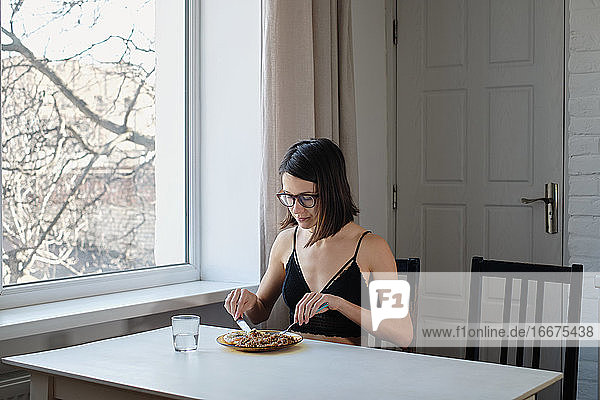 Junge Frau in Unterwäsche beim Frühstück am Tisch
