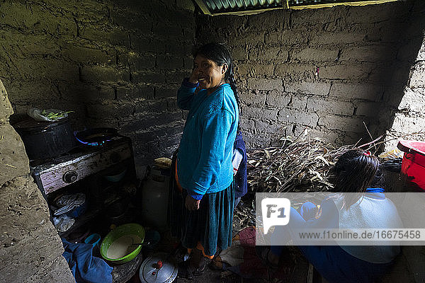 Lächelnde Frau  die mit ihrer Tochter in der Küche steht  während eines Gastaufenthalts auf der Insel Amantani  Peru
