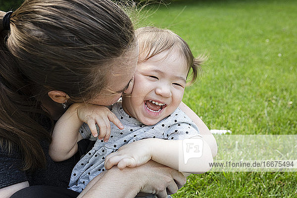 Happy Toddler Daughter Laughs As Mother Snuggles Her Closely