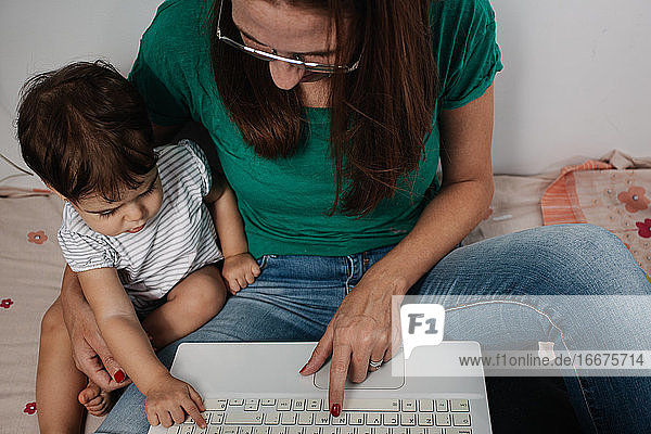 Mother with little kid using laptop at home