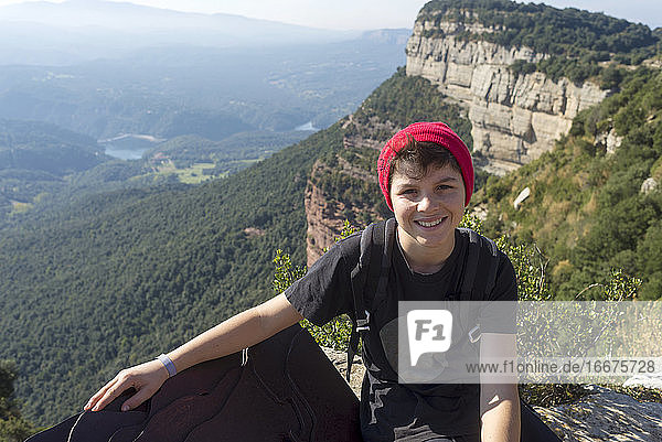 Portrait of a young male with wool red hat sitting against mountain
