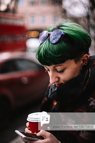 Porträt einer Hipster-Frau  die ein Smartphone benutzt  während sie in der Stadt steht