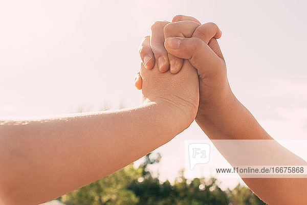 Union der ineinander verschlungenen Hände zwei Schwestern in den Hintergrund des blauen Himmels  Familie