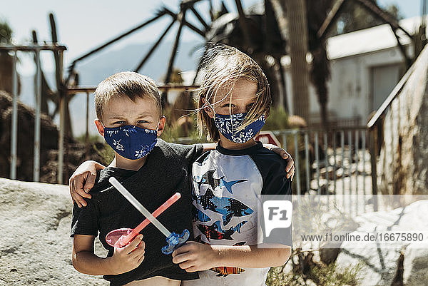 Close up portrait of young brothers with masks on outside on vacation