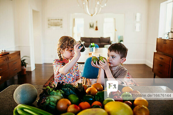 Junge und Mädchen sitzen an der Küchentheke mit Obst und Gemüse