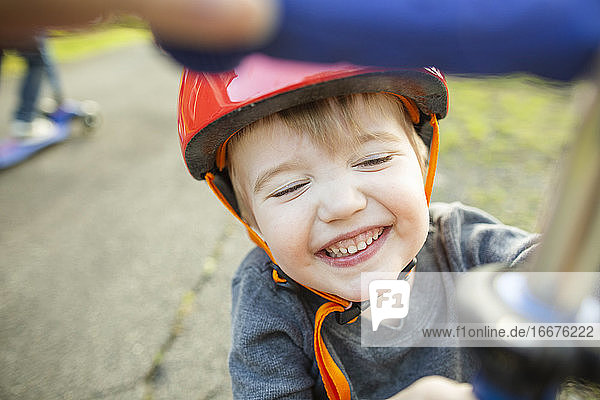 Smiling young boy wearing red helmet while playing outside at home