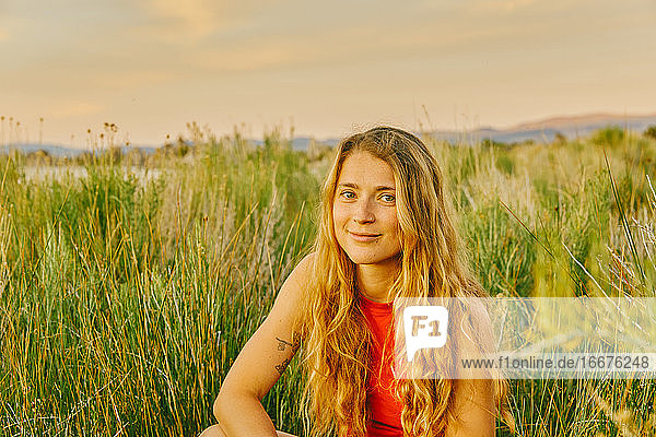 Junge Frau sitzt im hohen Gras am Mono Lake in Nordkalifornien.