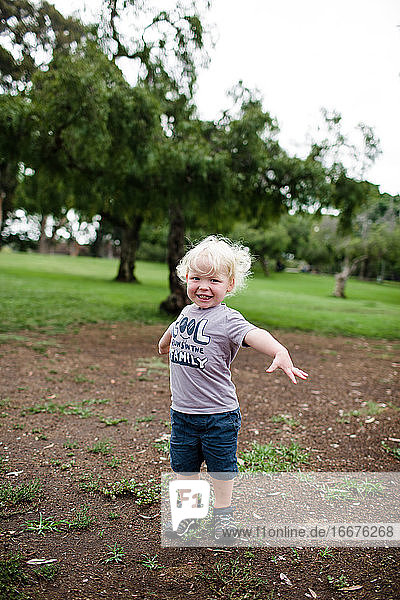 Zweijähriges Mädchen lächelt für die Kamera und steht im Park