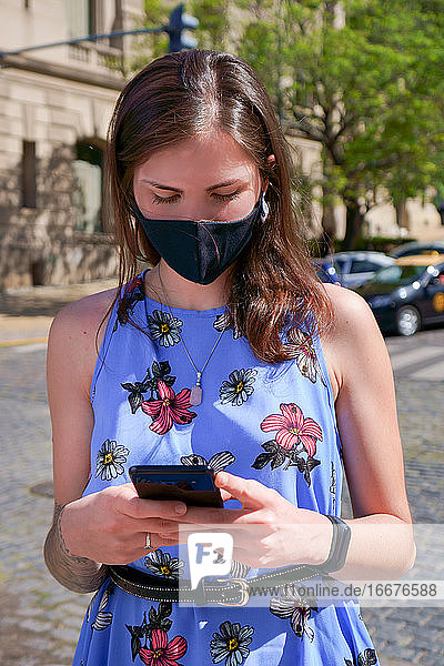 Frau im Freien mit Maske und Mobiltelefon