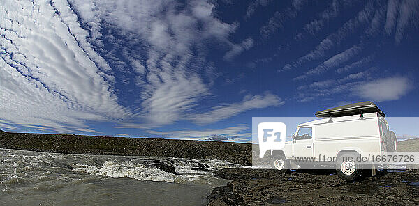 weißer SUV am Rande eines Wasserfalls