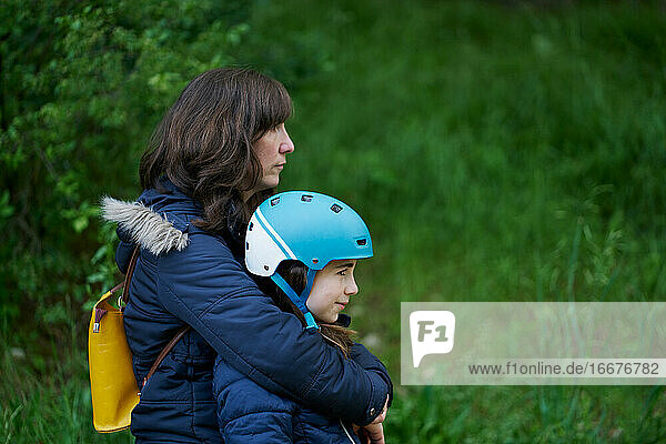mother hugs her daughter with a helmet