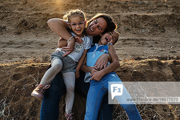 a mother sitting on the field plays with her daughters