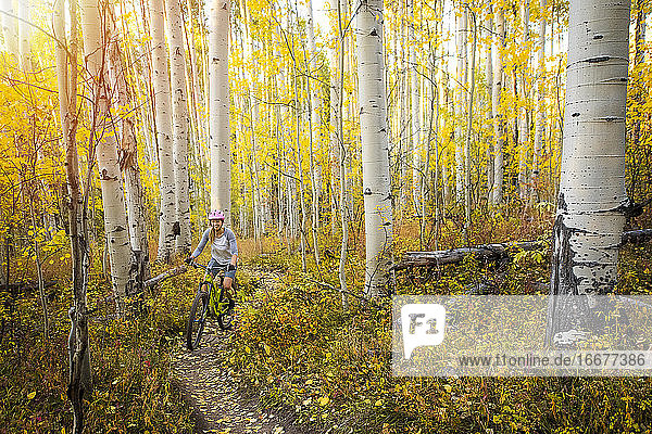 Frau beim Mountainbiking inmitten von Herbstbäumen im Wald