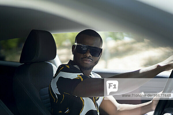 junger afrikanischer Mann fährt sein weißes Auto