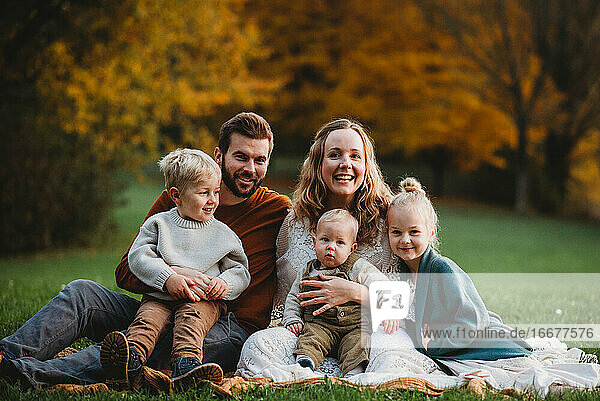 Good looking family sitting in a park with colorful Fall trees