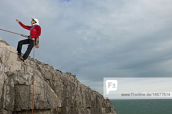 Weibliche Kletterin beim Abseilen von einer Seeklippe in Swanage / England