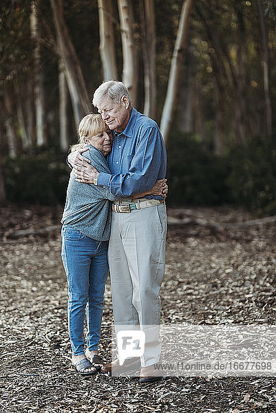 Portrait of senior retired adult couple embracing in forest