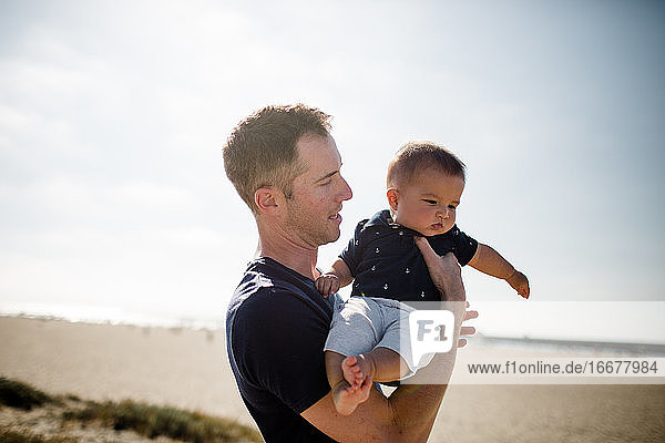 Father Holding Infant Son on Beach