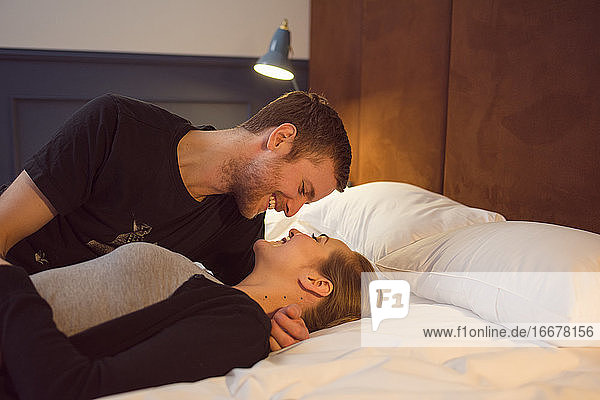 Optimistisches Paar kuschelnd auf dem Bett