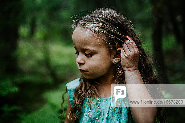 Young biracial girl looking down and fixing hair