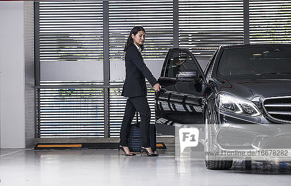 Geschäftsfrau steigt auf einem modernen Parkplatz in ihr Luxusauto ein