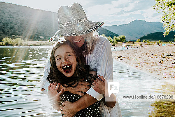 Mutter und Tochter umarmen sich und lachen  während sie in einem See stehen